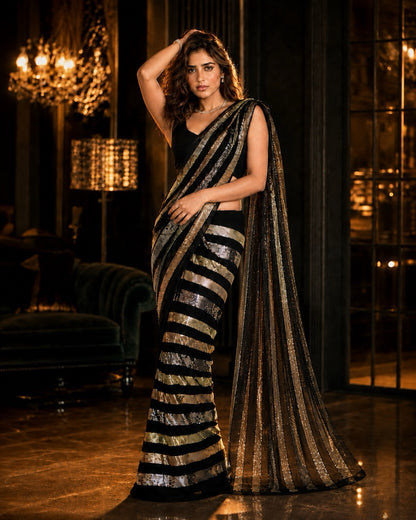 Black Bollywood Designer Saree with metallic gold stripes of radiant sequin, by Masnavi, modeled by a woman, front view